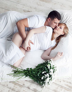 Муж и беременная жена на кровати